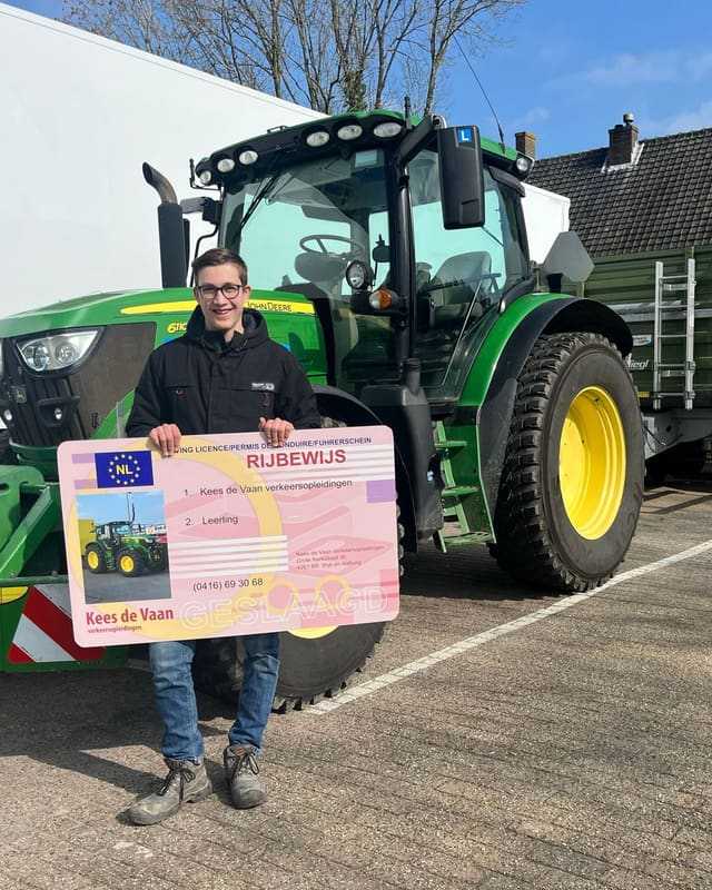 Geslaagde cursist houdt het rijbewijsbord omhoog voor de groene lestrekker van Kees de Vaan