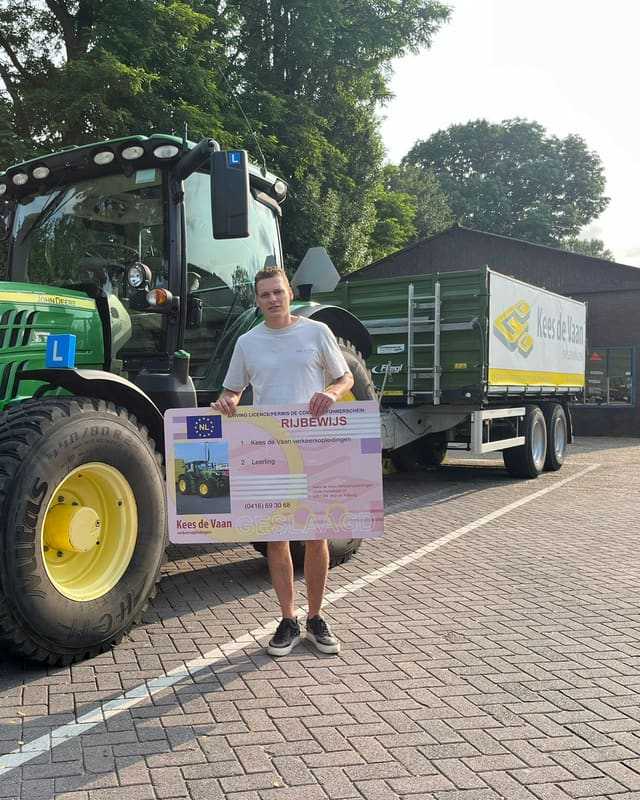 Geslaagd voor het T-rijbewijs: cursist naast een groene lestrekker met aanhangwagen