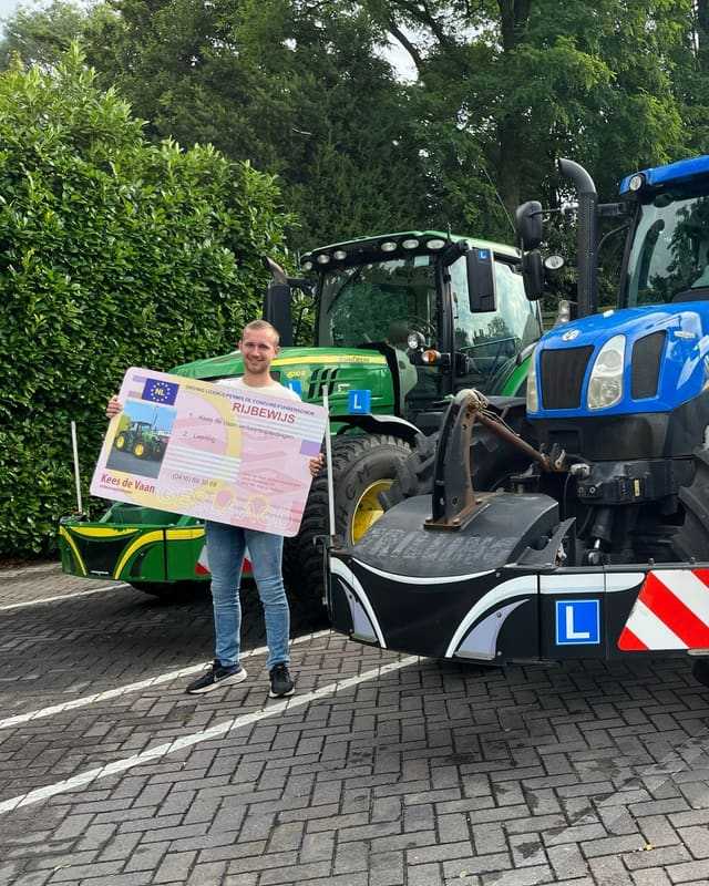 Geslaagd voor het trekkerrijbewijs: cursist tussen een groene en een blauwe lestrekker