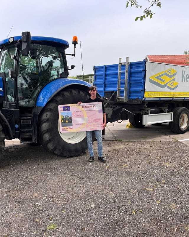 Geslaagd voor het trekkerrijbewijs: cursist voor een blauwe lestrekker met kipper van Kees de Vaan