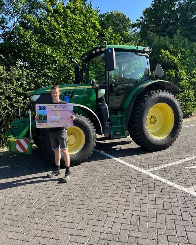 Geslaagde cursist met rijbewijsbord voor een groene lestrekker op een zonnige dag