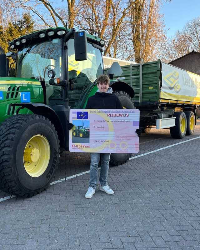 Geslaagde cursist met rijbewijsbord en witte sneakers voor een groene lestrekker