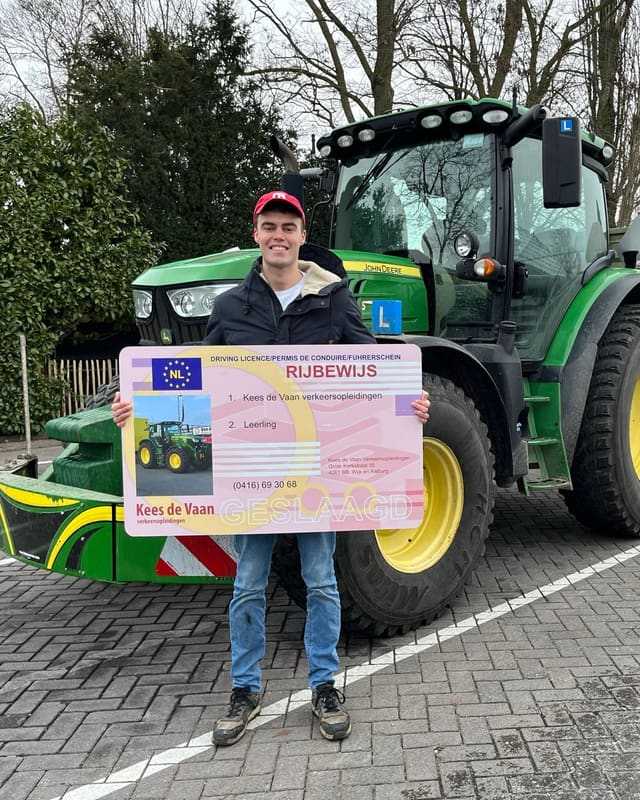 Geslaagde cursist met rode pet en rijbewijsbord voor een groene lestrekker