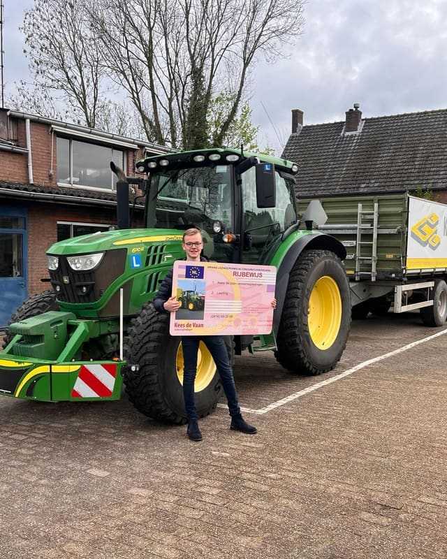 Geslaagde cursist met rijbewijsbord voor een groene lestrekker en aanhangwagen in het voorjaar