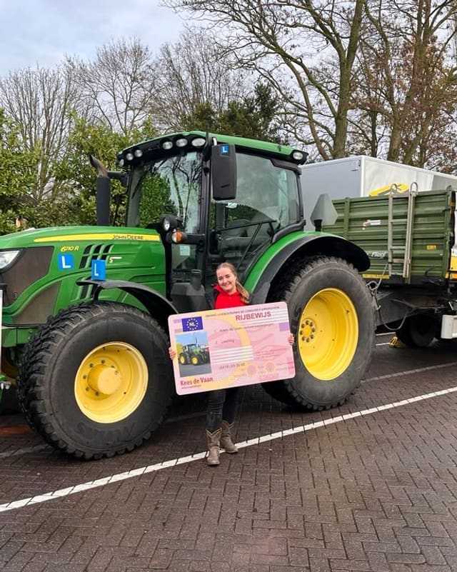 Geslaagd voor het T-rijbewijs: cursist met rijbewijsbord bij een groene lestrekker