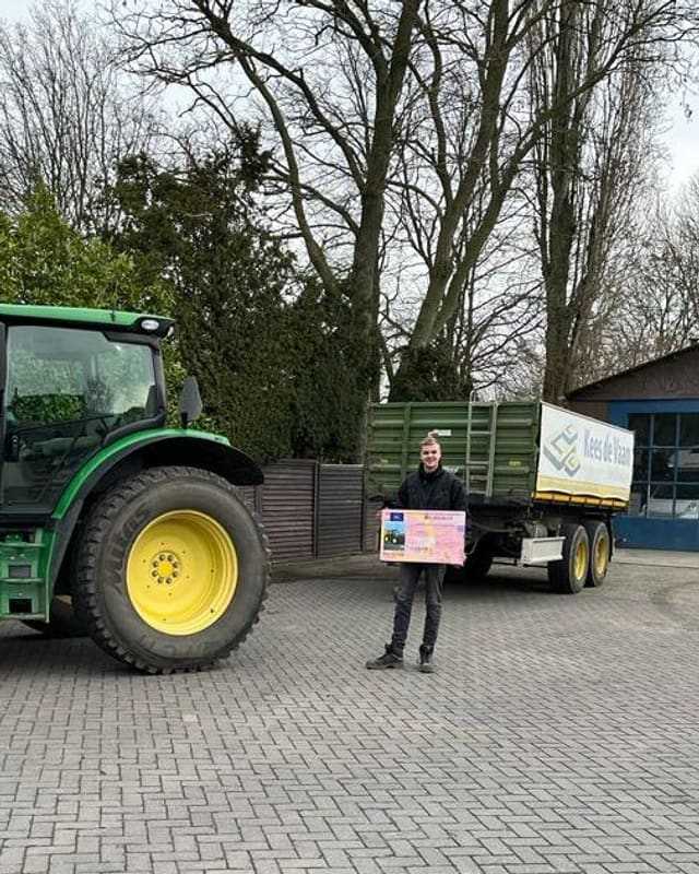 Geslaagd voor het T-rijbewijs: cursist met rijbewijsbord bij de kipper van Kees de Vaan