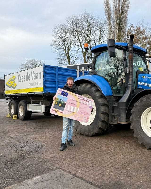 Geslaagd voor het T-rijbewijs: cursist met rijbewijsbord bij een blauwe lestrekker en de kipper van Kees de Vaan