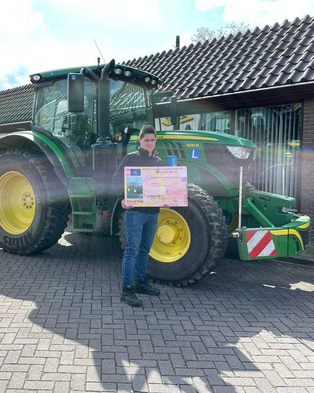 Geslaagd voor het T-rijbewijs: cursist met rijbewijsbord voor een groene lestrekker in de ochtendzon