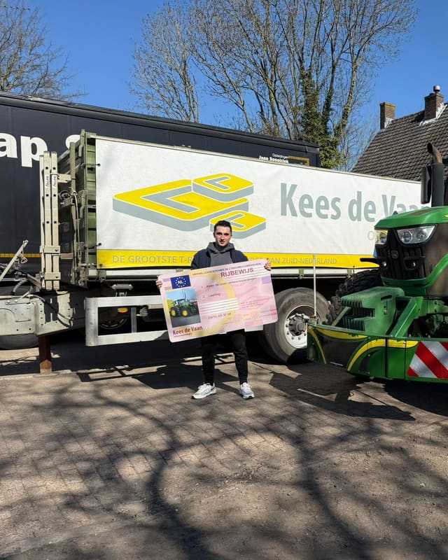 Geslaagd voor het T-rijbewijs: cursist met rijbewijsbord voor de oplegger van Kees de Vaan
