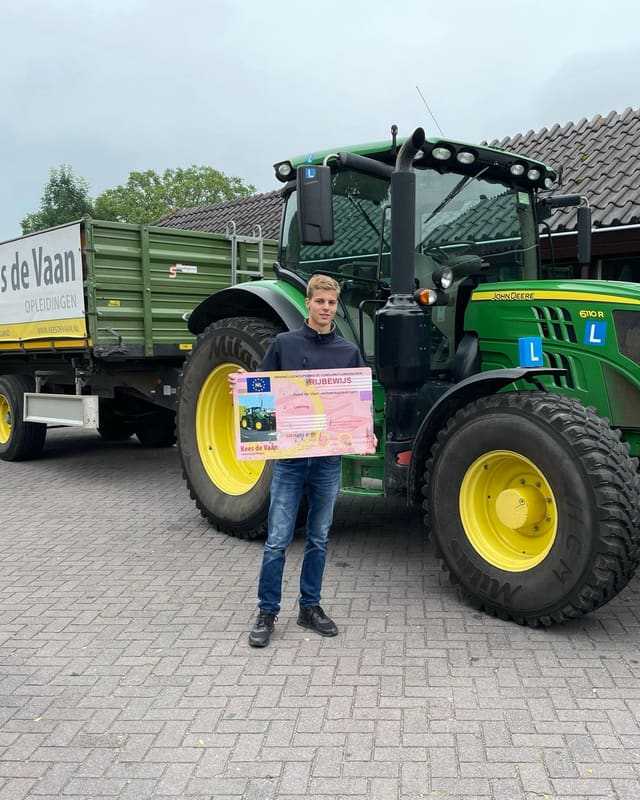 Geslaagd voor het T-rijbewijs: cursist met rijbewijsbord voor een groene lestrekker bij het leslokaal