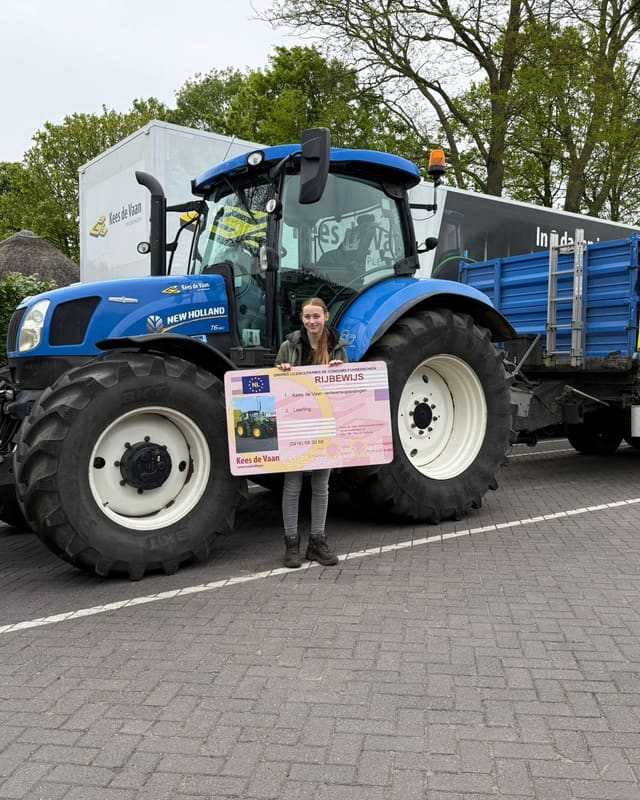 Geslaagde cursist met lang haar en rijbewijsbord voor een blauwe lestrekker