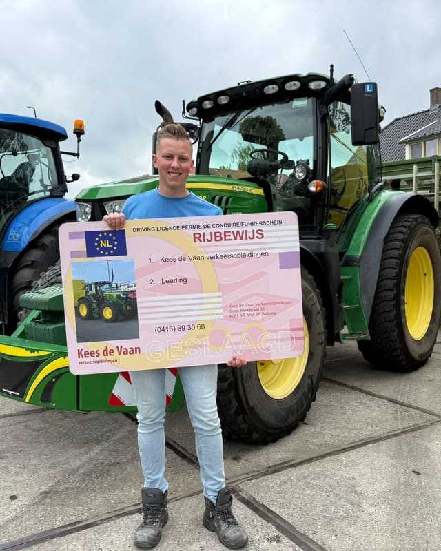 Geslaagde cursist in lichtblauw shirt met groot rijbewijsbord bij de lestrekkers