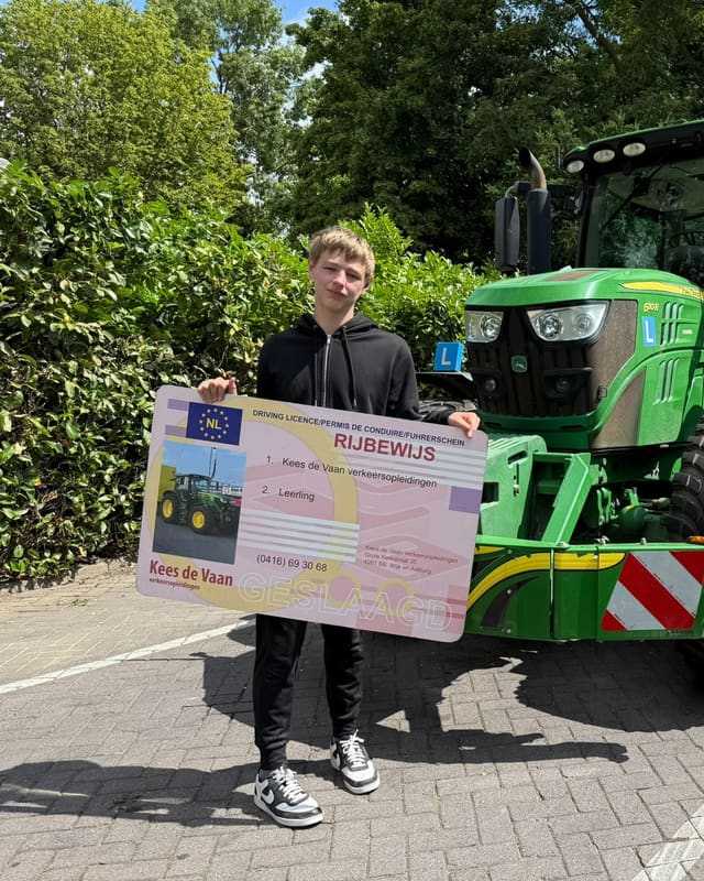 Geslaagde cursist in zwarte hoodie met groot rijbewijsbord voor een groene lestrekker